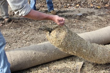 John demonstrates the weight difference between his compost-blended FilterMitt and the StrawFilterMitt used for erosion control. The weight of the compost-blended tubes allows them to withstand heavy, rapid flows.  The straw wattles are more appropriate for flat surfaces and lower flow rates. 